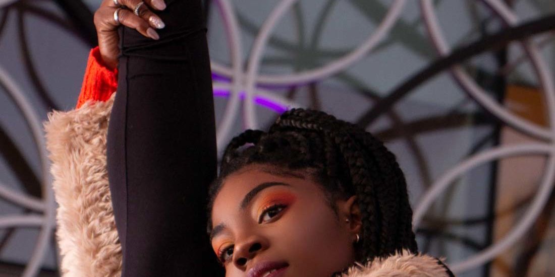 Birmingham street dancer posing her orange Nike shoes while stretching her leg in a split