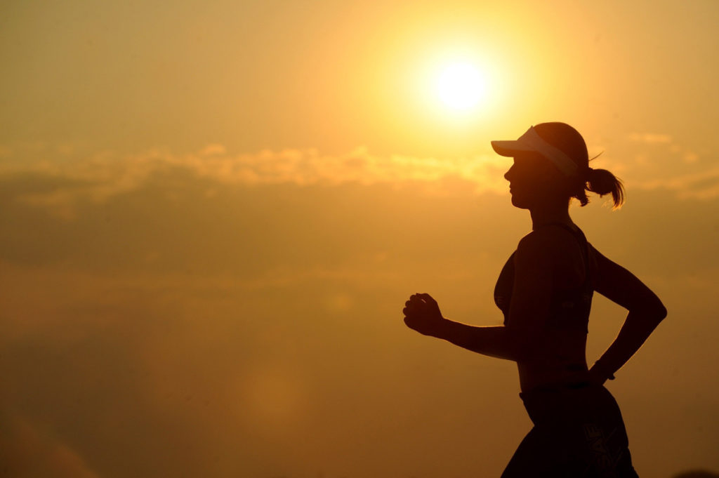 a workout for photographers, a woman is running during golden hour 