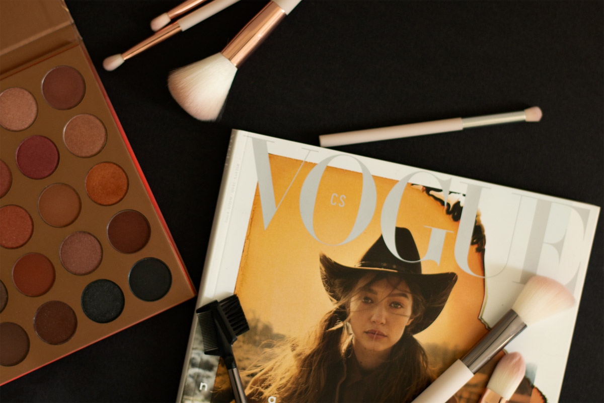 Vogue magazine, makeup brushes, eyeshadow pallet on the black background