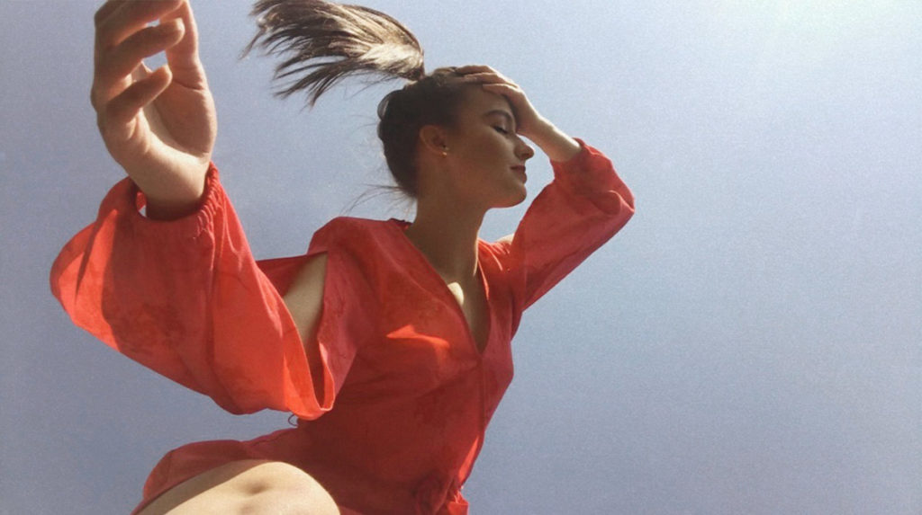 A woman in red posing in front of blue sky 