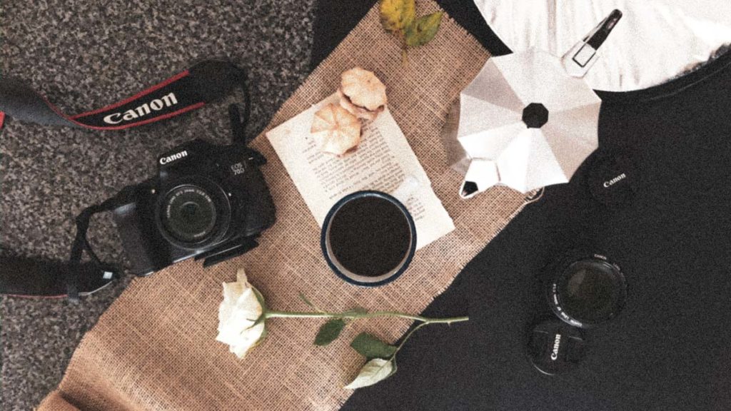 a flatlay image with canon camera, coffee and camera lenses. Business tips for photographers during covid-19