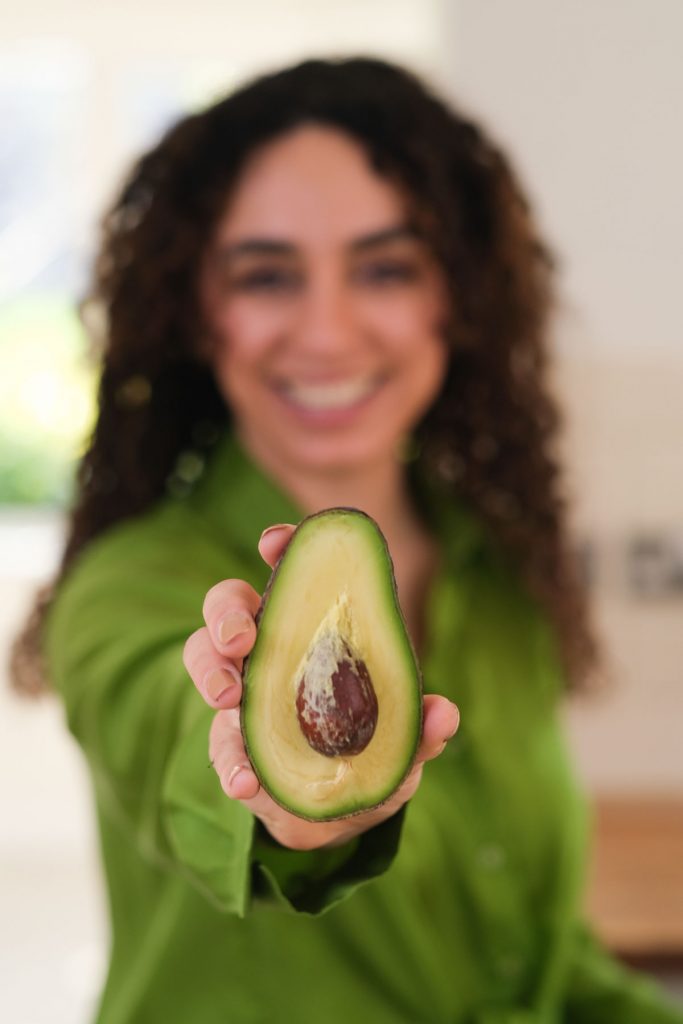 nutritionist posing with a cut avocado smiling