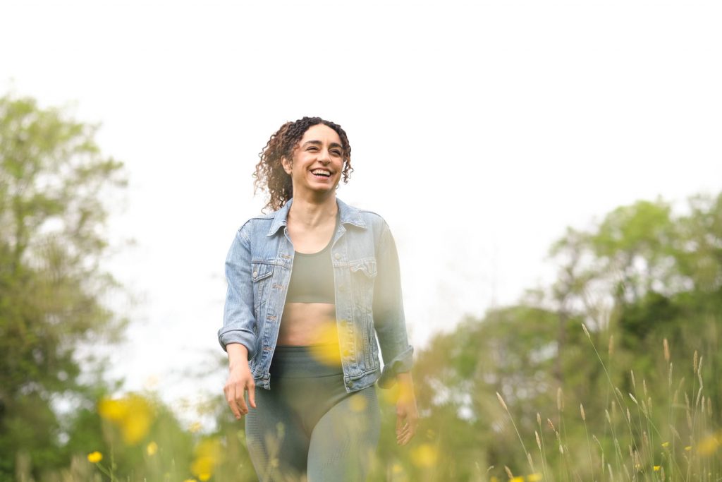 woman walking across the field with yellow flowers smiling