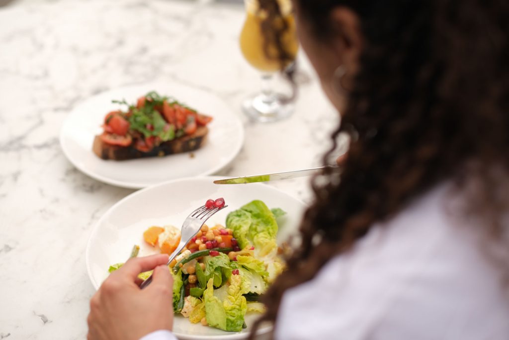 a detail photo of salad over a woman's shoulder