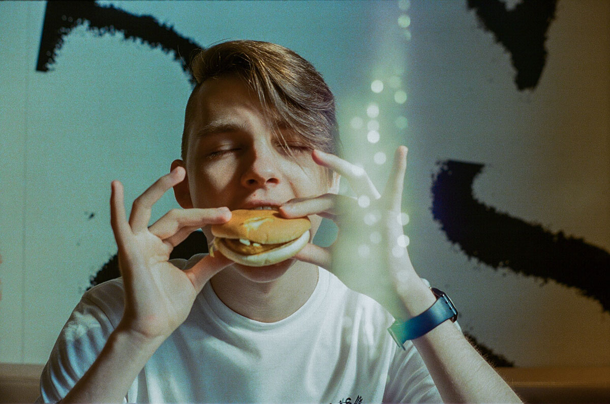 5 awesome benefits of shooting on film. Film photography, analog photography, 35mm photography. A young man eating a hamburger.  