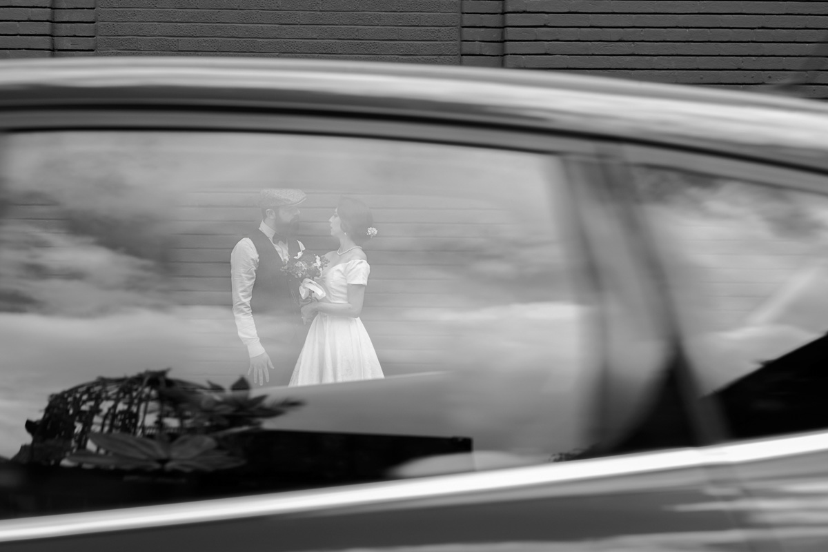 Bride and groom photographed through a passing car's window