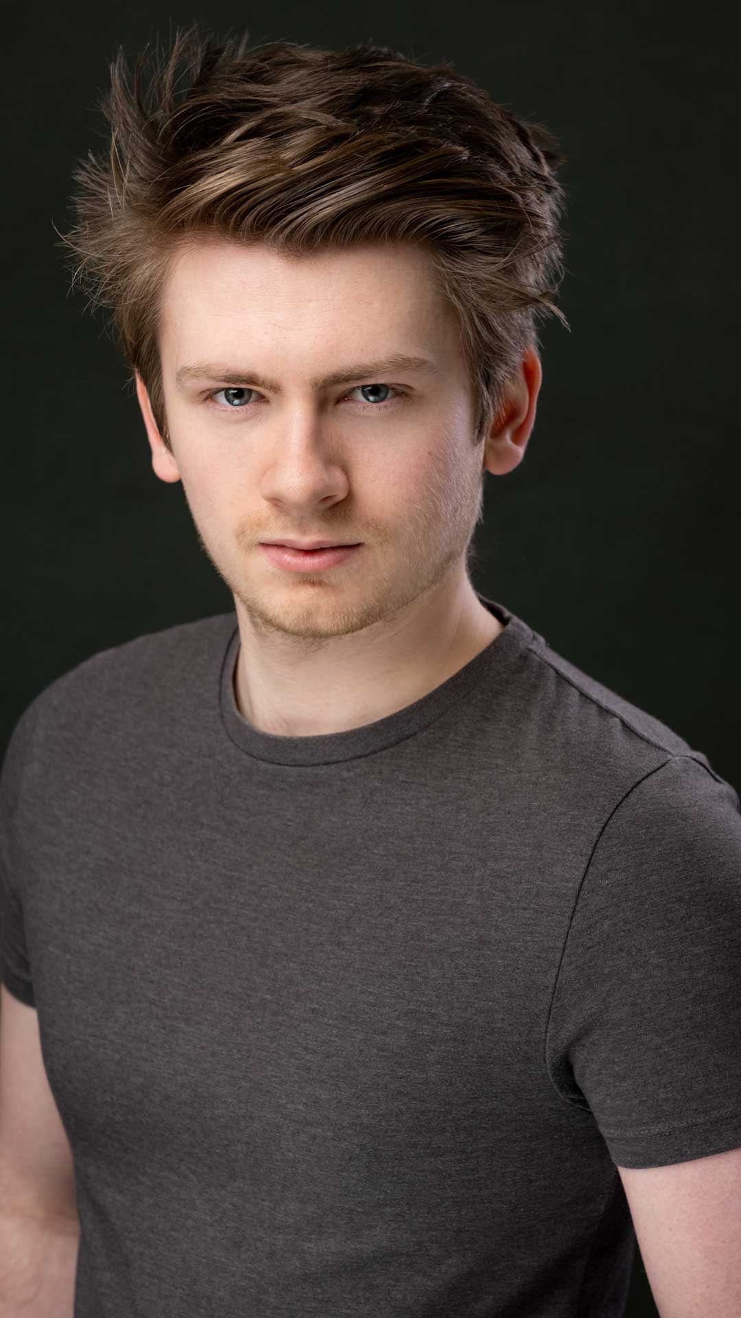 Male actor headshot in a studio dark background