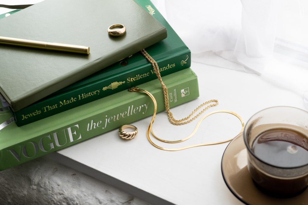 Content Ideas for service-based businesses: Branding photography for jewellery copywriter. Books about jewellery with golden rings and chains, and coffee.