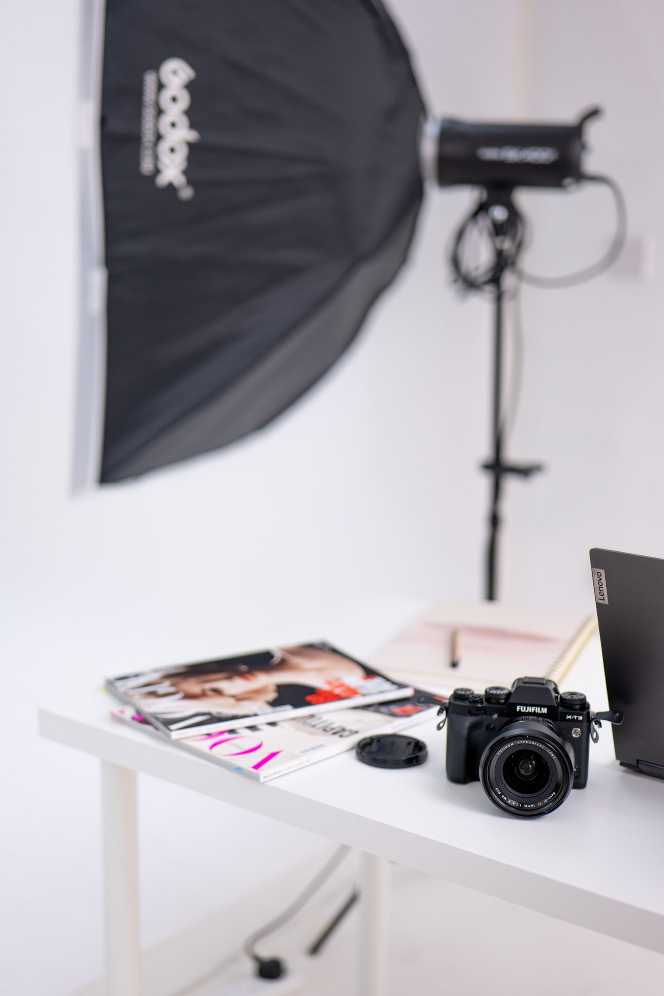 photoshoot bts - camera, laptop and Vogue magazines on the table
