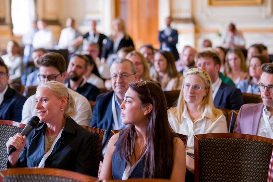 conference audience, a blonde woman is asking a question