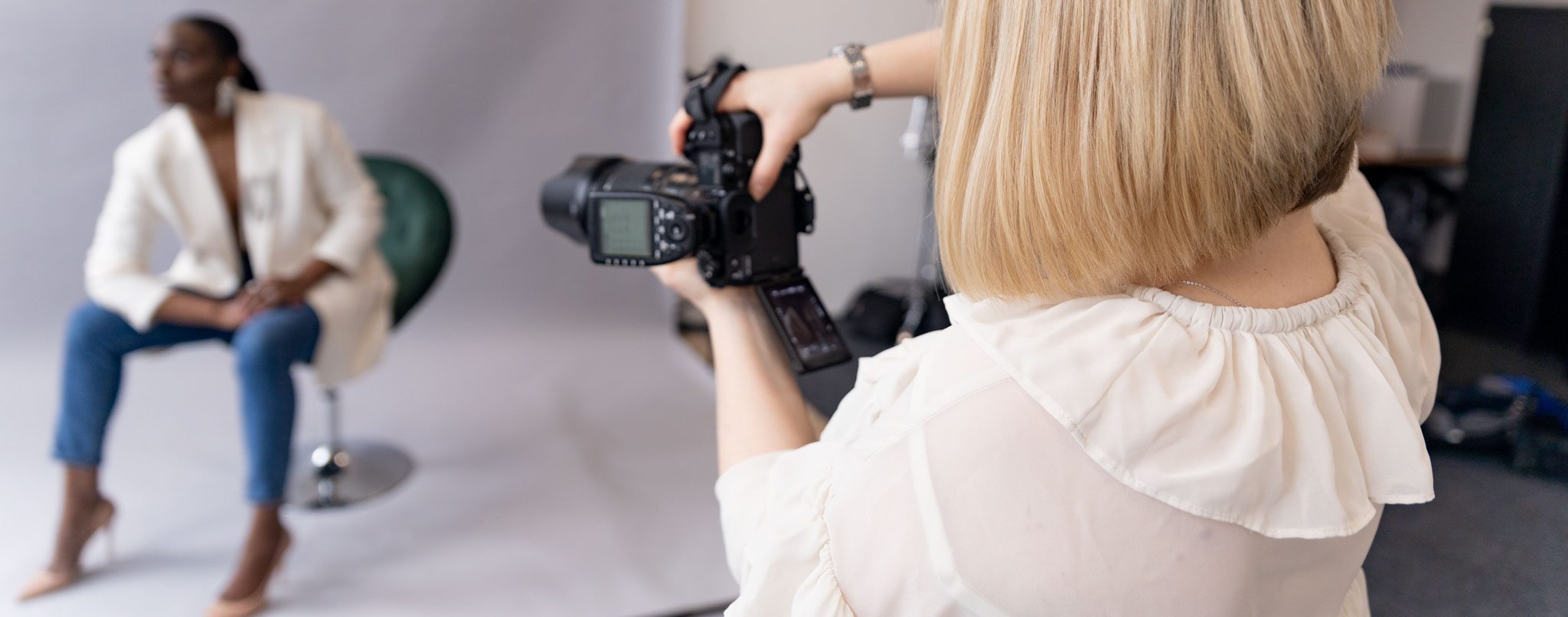 Studio photoshoot behind the scenes, a female photographer taking photos of a professional model