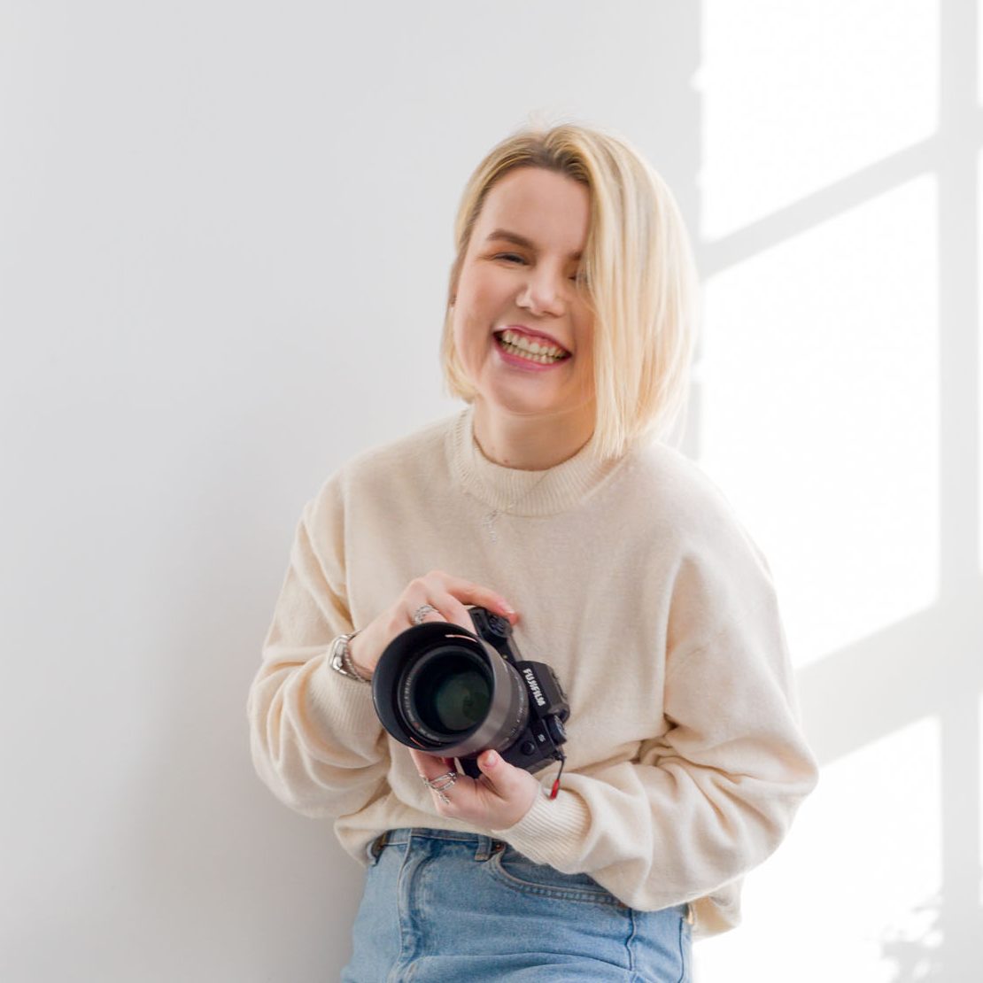 professional portrait photographer laughing in front of white background