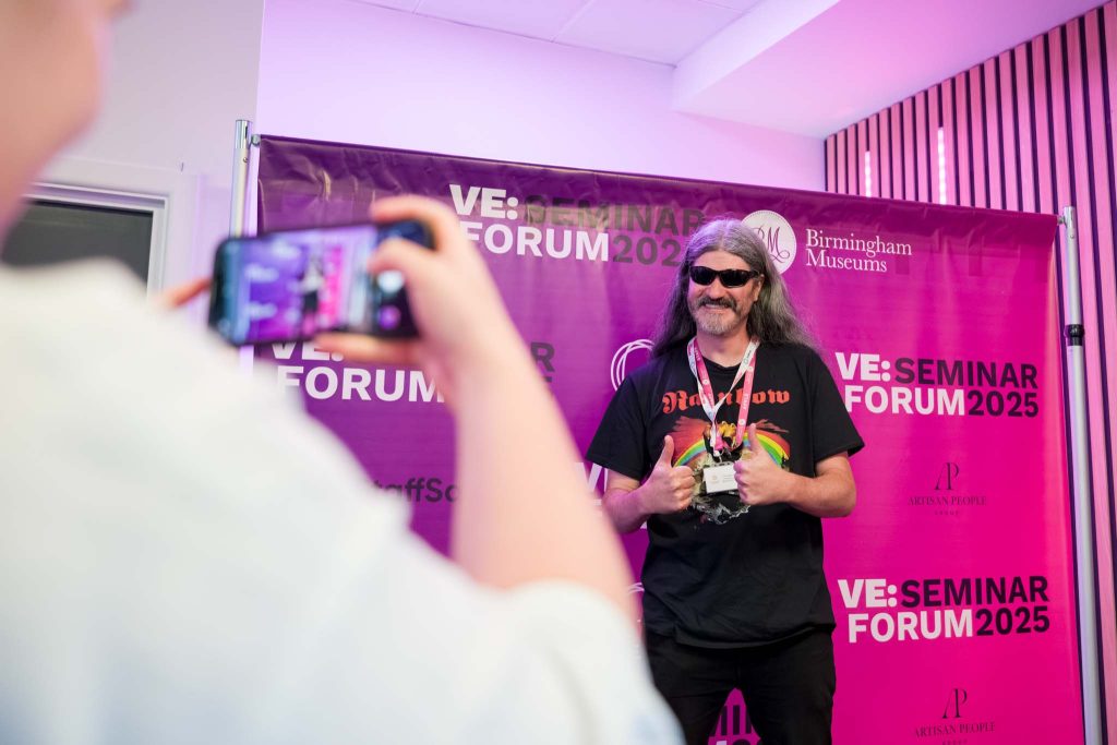 conference event photography, a guest is posing with a branded banner