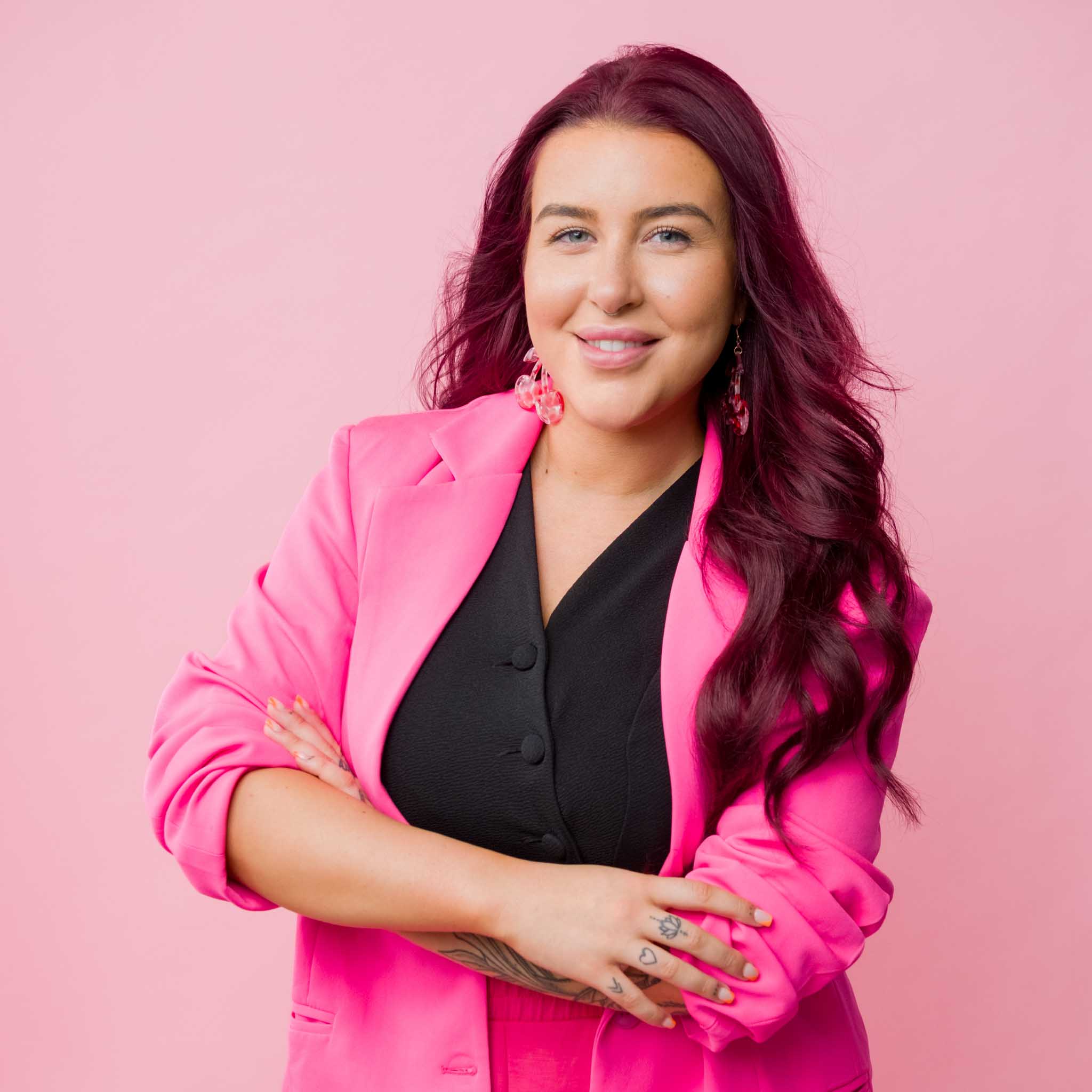 creative business portrait of a female entrepreneur wearing pink suit posing in front of a pink backdrop