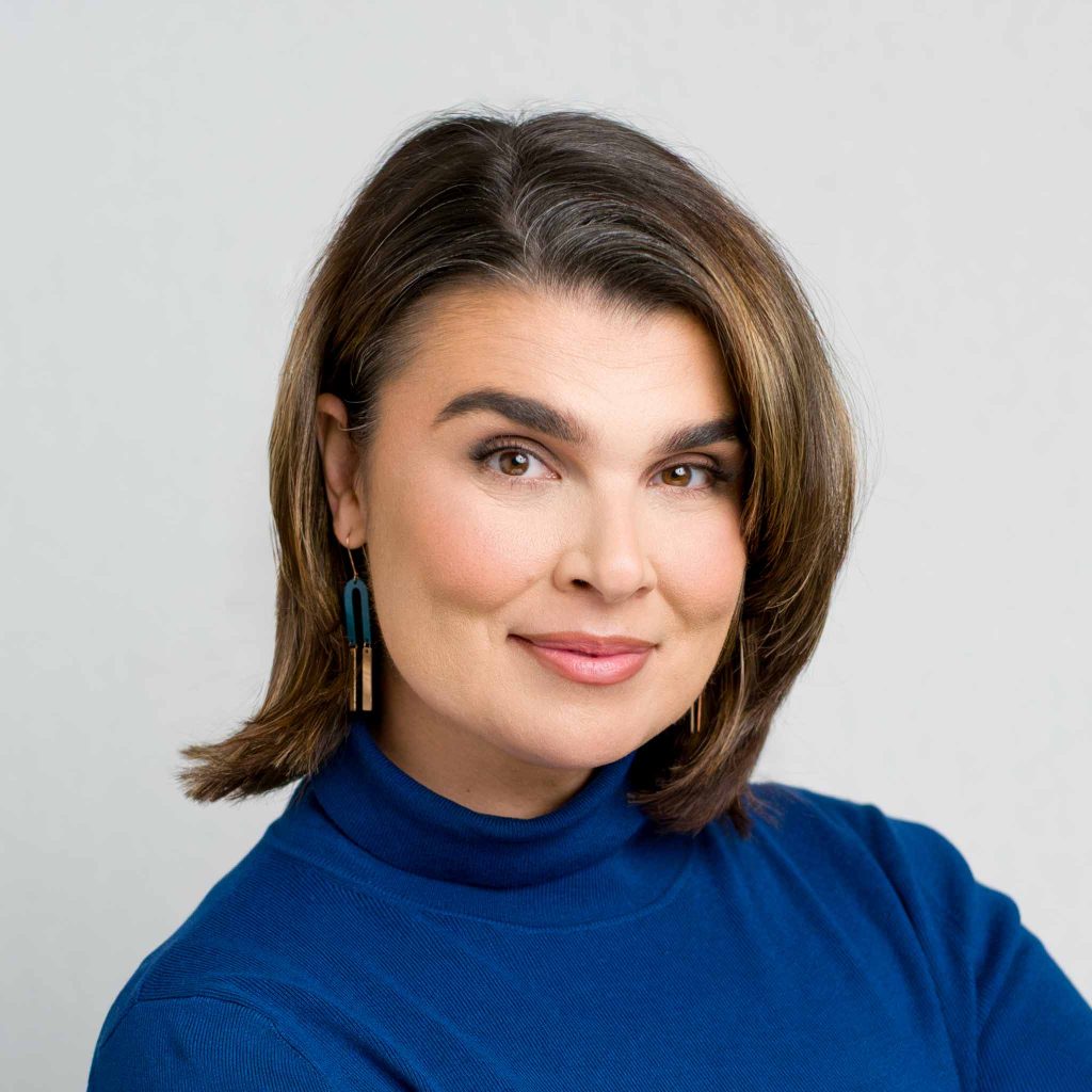 closeup LinkedIn portrait of a woman smiling in front of light grey background