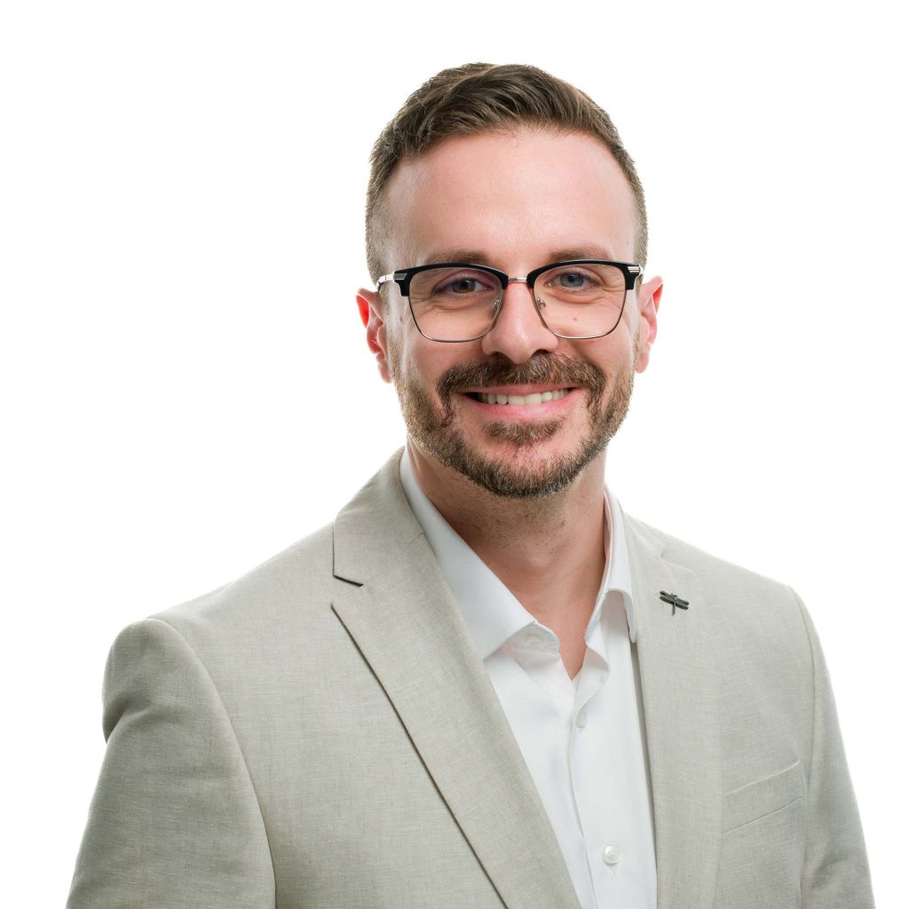 LinkedIn headshot portrait of a man wearing glasses and smiling