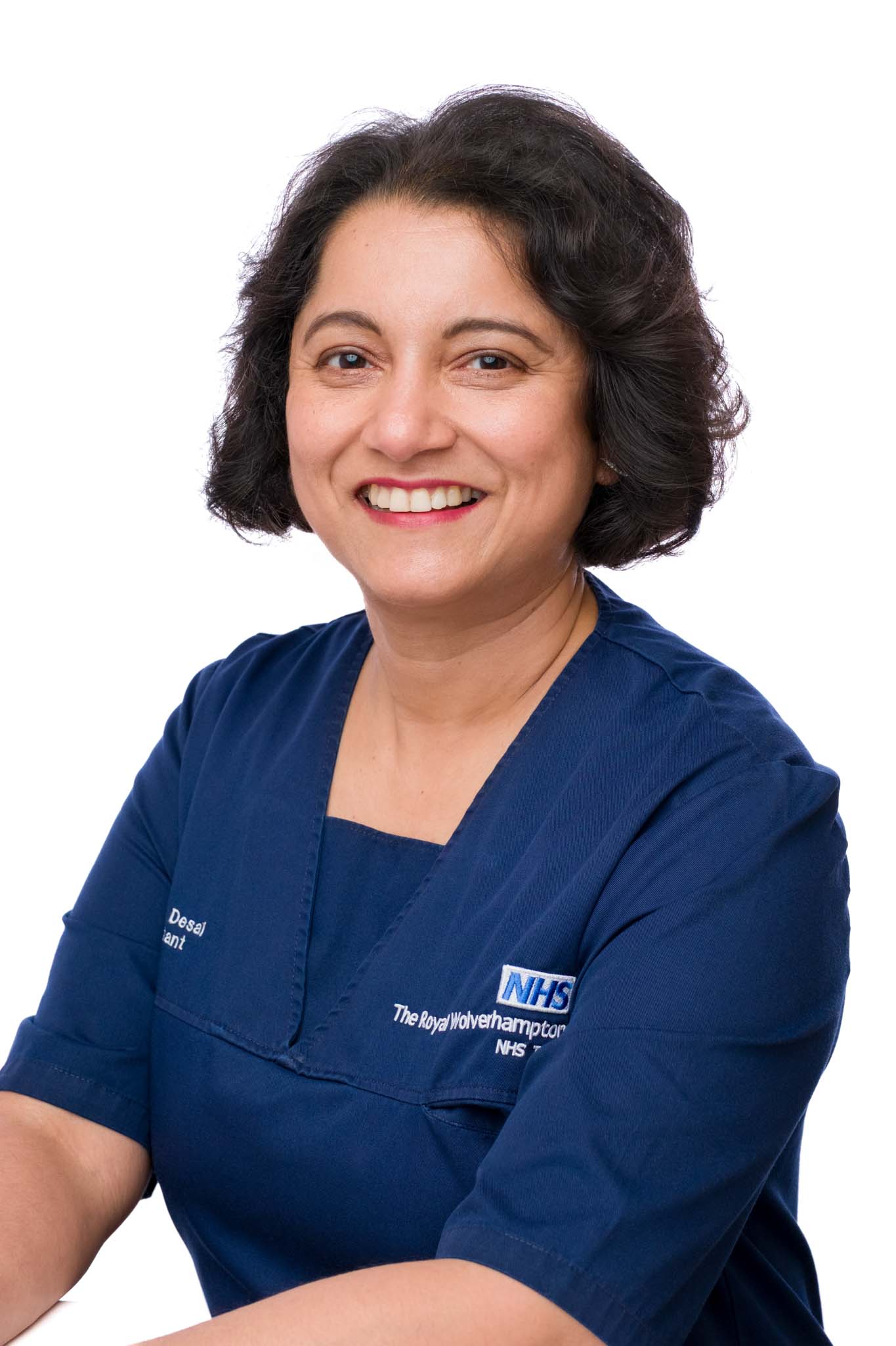 professional headshot of an NHS doctor posing in front of white background smiling