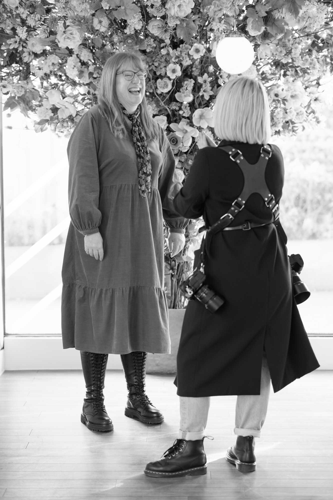 behind the scenes of a headshot photoshoot, a woman laughing whilst posing for the camera